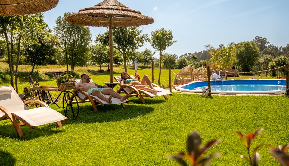 Zona da piscina comum, com espreguiçadeiras e dois hóspedes a relaxar