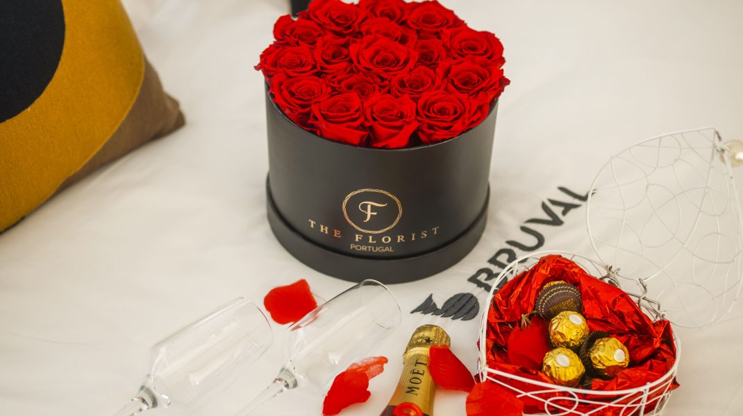 Bouquet de rosas frescas The Florist, garrafa de Moët Chandon e bombons de chocolate sobre a cama com o logo da Bruval